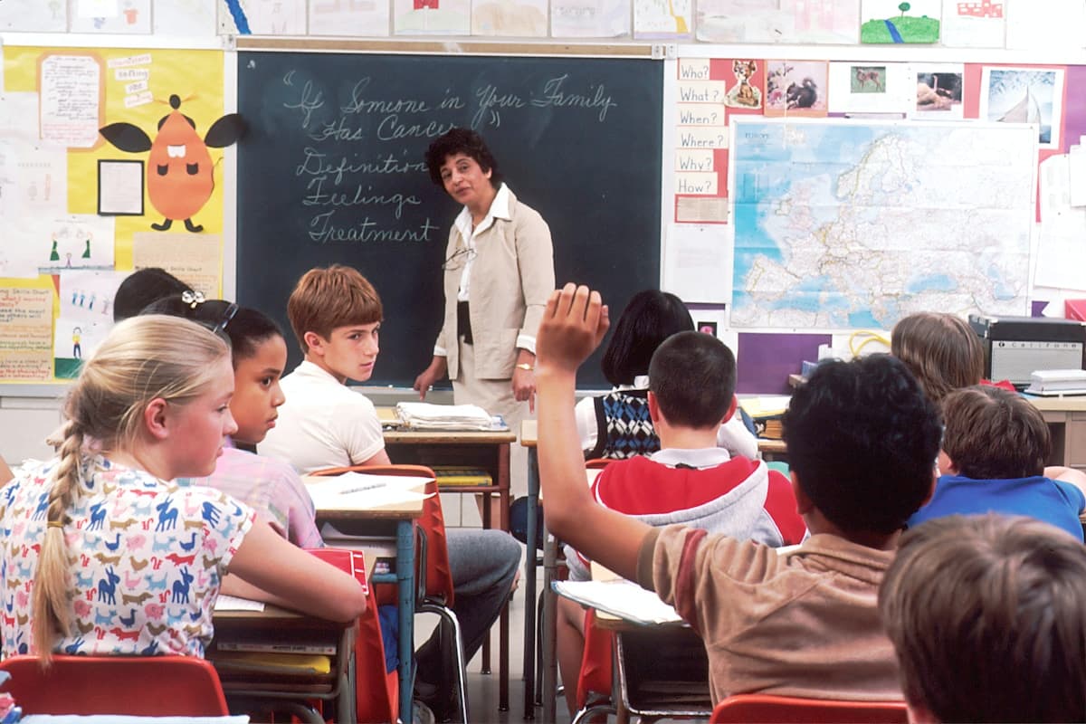 An elementary classroom with a student raising a hand