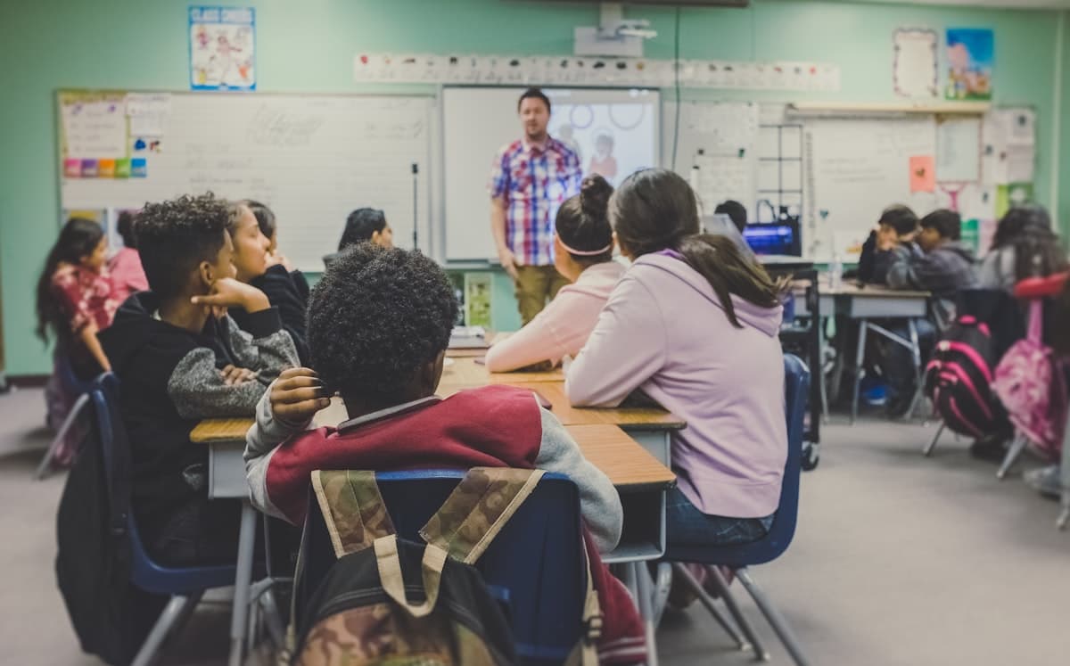 A teacher facilitating a lively, diverse classroom of engaged students