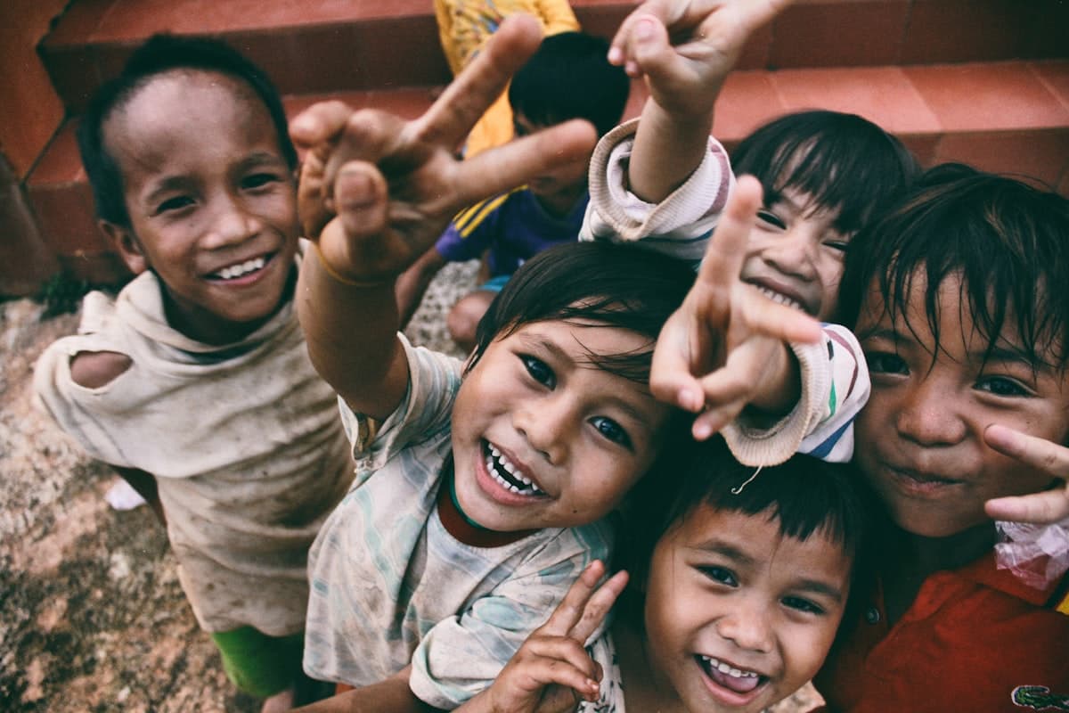 A group of joyful children smiling and reaching toward the camera